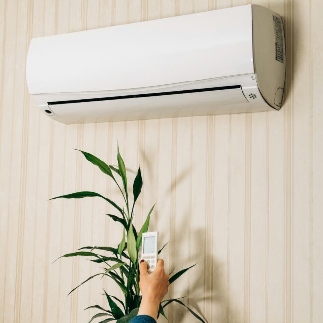 person holding remote up to air conditioning unit