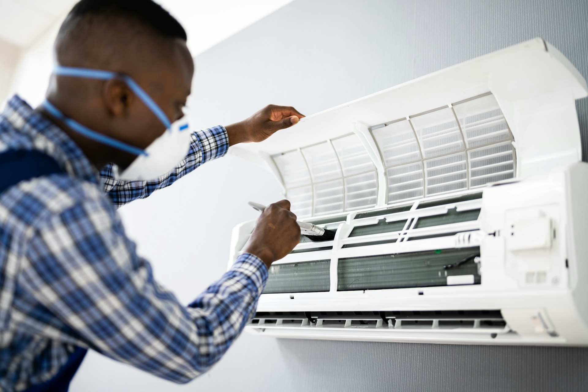 A HVAC repair expert cleaning and performing maintenance on an HVAC system, inspecting and adjusting components inside.