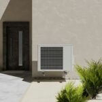 Outdoor HVAC unit placed on a concrete wall, surrounded by plants. The units casing and ventilation grills are clearly visible, with no debris or obstructions around it.